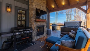 A cozy outdoor living area with a stone fireplace, a grill, and a comfortable seating area. - Hidden Gem at Eagles Nest (Banner Elk)