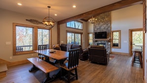 A spacious living area with a wooden dining table, leather sofas, and a stone fireplace. - Hidden Gem at Eagles Nest (Banner Elk)