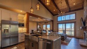 A spacious kitchen with a large island, stainless steel appliances, and a stone fireplace. - Hidden Gem at Eagles Nest (Banner Elk)