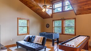 A cozy room with a foosball table, a sofa, and a dartboard. - Skyland Cabin (Boone)