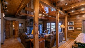 A rustic cabin interior with wooden beams, a stone fireplace, and a cozy seating area. - Gratitude (Blowing Rock)