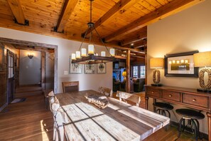 A rustic wooden dining area with a large table, chairs, and a chandelier. - Gratitude (Blowing Rock)