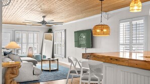 A spacious room with a high ceiling, a ceiling fan, a large mirror, a wooden bar counter, and a sign for 'ROYAL STAYS'. - Grove Cove | Beach 2 Min | Dog-Friendly | Hot Tub (North Myrtle Beach)