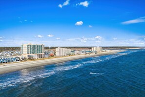 Paisagem costeira com hotéis na praia e um píer que se estende para o oceano.