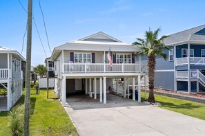 A two-story house with a balcony, a flag, and a palm tree.