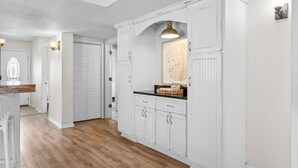 Een keuken met witte kasten, een houten aanrechtblad en een hanglamp.