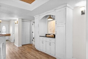 A kitchen with white cabinetry, a wooden countertop, and a hanging light fixture.