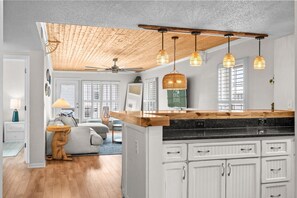 Una cocina moderna con armarios blancos, encimera de madera y luces colgantes.