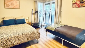 A bedroom with two beds, a window with curtains, a radiator, and a poster on the wall. - Buller Street Home (Charlestown)