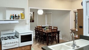 A compact kitchen with a gas stove, a sink, and a dining area with chairs. - Buller Street Home (Charlestown)