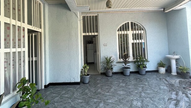 A covered patio area with a tiled floor, potted plants, a sink, and a window with bars. - Spacious 2bed & 2bath Villa (Bishofitu)