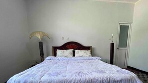 A neatly made bed with a floral-patterned bedspread, a wooden headboard, and a bedside lamp. - Spacious 2bed & 2bath Villa (Bishofitu)
