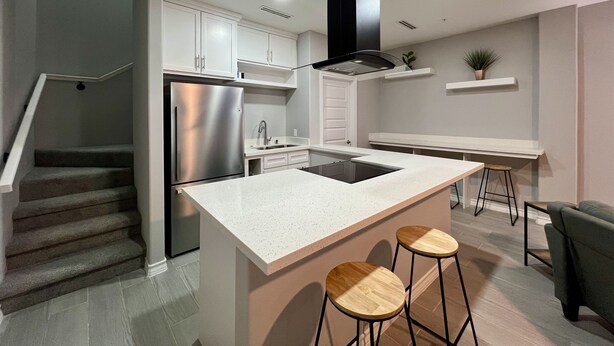 A modern kitchen with a central island, stainless steel appliances, and a staircase leading to another level. - Villa Escondida #2 -2BD- Straight Shot to SpaceX! (Brownsville)