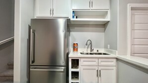 A compact kitchen with white cabinets, a stainless steel refrigerator, a sink, and a towel dispenser. - Villa Escondida #2 -2BD- Straight Shot to SpaceX! (Brownsville)
