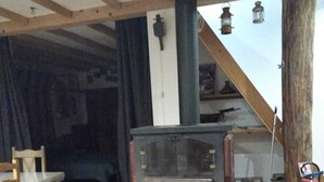 Une pièce rustique avec un poêle à bois, une chaise en bois et un escalier.