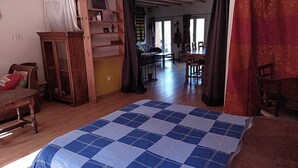 Une pièce spacieuse avec un grand lit, des meubles en bois, une bibliothèque et un coin repas.