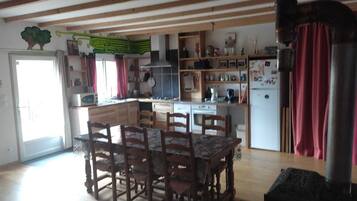 Una cocina con armarios de madera, una mesa de comedor con sillas, una estufa y un refrigerador.