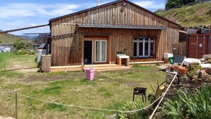 Une cabane en bois avec un porche à l’avant, un petit abri attenant et une cour clôturée.