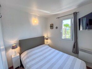 Cozy retreat with a single bed, nightstand, and flat-screen TV, offering a peaceful view of the surrounding greenery.