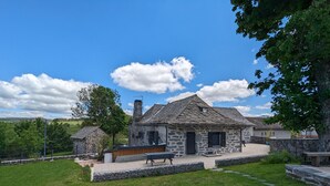 A stone house with a sloped roof, a chimney, and a small porch area. - Cozy Cottage Near Ski Resort and UNESCO Sites, Garden, 3BR, Fully Equipped in Saint-Front (Saint-Front)