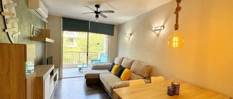 A modern living room with a sofa, a wooden dining table, and a ceiling fan.