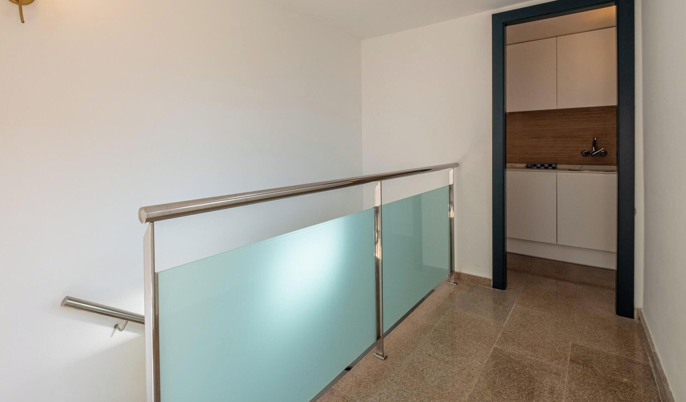 Een modern appartement met een glazen balkon, een keuken met houten kastjes en een betegelde vloer.