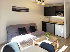A compact living space with a sofa, a dining table, a small kitchen area with a microwave and a refrigerator, and a potted plant. - Renovated studio, quiet, ski-in/ski-out, 6 people, Les Orres (Les Orres)