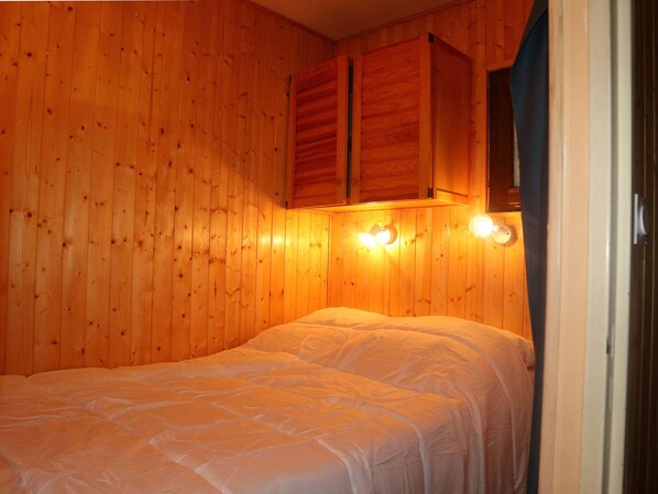 A wooden-paneled room with a bed, two wall-mounted lights, and a wooden cabinet above the bed. - Renovated studio, quiet, ski-in/ski-out, 6 people, Les Orres (Les Orres)