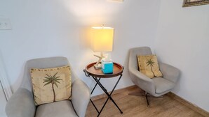Dos sillones con cojines de hojas de palma, una mesita con una lámpara y una caja de pañuelos.