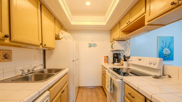 Una cocina con electrodomésticos blancos, armarios de madera, un microondas y una estufa.