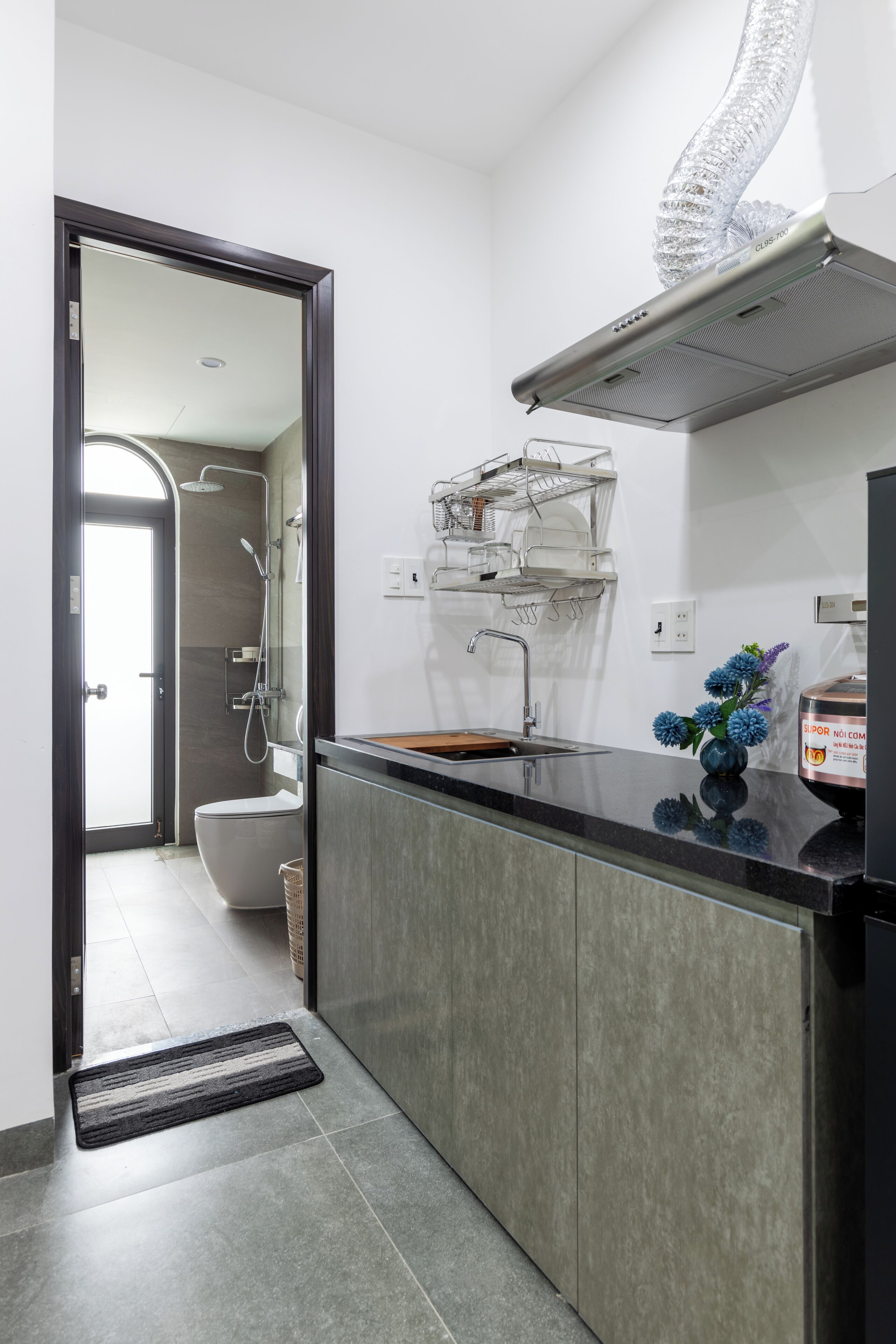 A modern kitchen with a built-in oven, a stainless steel sink, and a compact dishwasher.