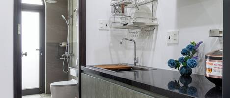 A modern kitchen with a built-in oven, a stainless steel sink, and a compact dishwasher.