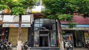 A multi-story building with a modern facade, a storefront with glass doors, and several parked motorcycles. - Saluton Apartment (Da Nang)