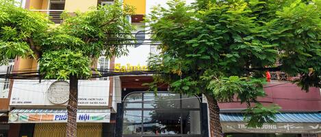 Un edificio de varios pisos con fachada moderna, una tienda con puertas de vidrio y varias motocicletas estacionadas.