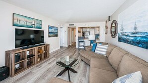 A living room with a TV, sofa, and coffee table. There is a kitchen in the background. - 1BR condo with pool, hot tub, kitchen, WiFi, and island views in St. Petersburg. (St. Petersburg)