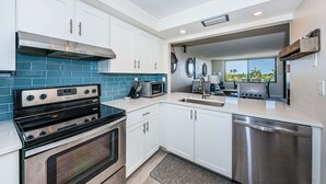 A modern kitchen with white cabinets, a black stove, a microwave, and a dishwasher. - 1BR condo with pool, hot tub, kitchen, WiFi, and island views in St. Petersburg. (St. Petersburg)
