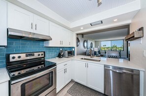 Una cucina moderna con mobili bianchi, un piano cottura nero, un forno a microonde ed una lavastoviglie.