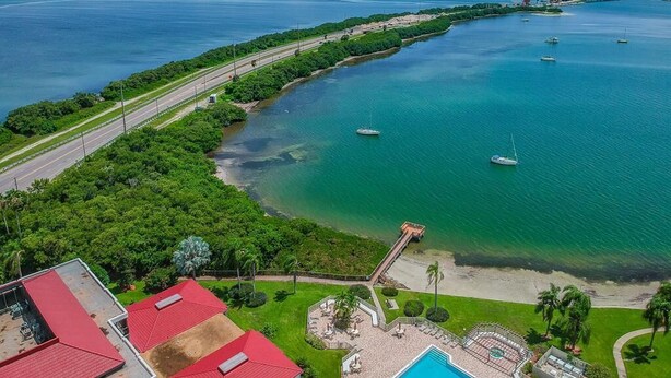 An aerial view of a coastal area with a swimming pool, a beach, and a road running parallel to the water. - 1BR condo with pool, hot tub, kitchen, WiFi, and island views in St. Petersburg. (St. Petersburg)
