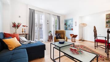Una sala de estar moderna con un sofá azul, una mesa de centro de vidrio y una silla roja.