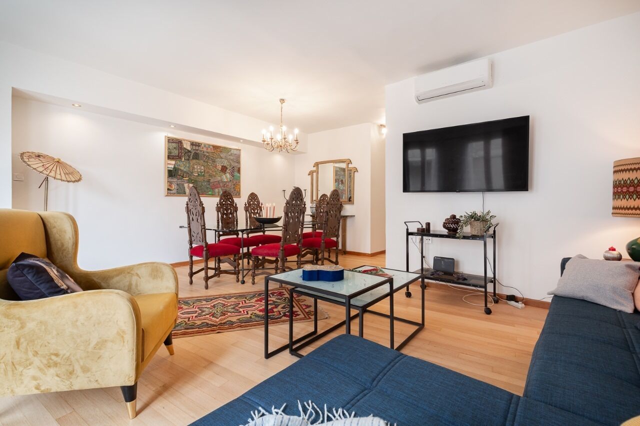 Una sala moderna con sofá, sillón, mesa de comedor y sillas.