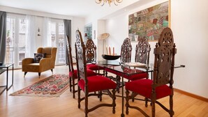 A dining area with a glass table and ornate chairs, a chandelier, and a large abstract painting on the wall. - Athenian Gate To Plaka (Athens)