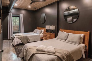 A bedroom with two beds, a wooden ceiling, a large mirror, and a window with curtains.