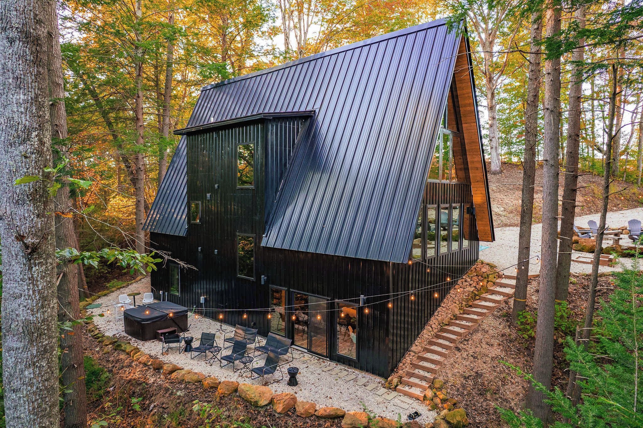 A modern cabin with a sloped roof, large windows, and a patio area with outdoor seating.
