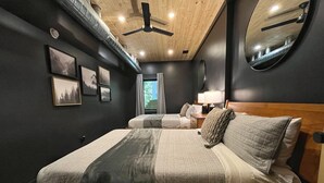 Ein Schlafzimmer mit einem Bett, Nachttischen, einem Spiegel und einem Deckenventilator.