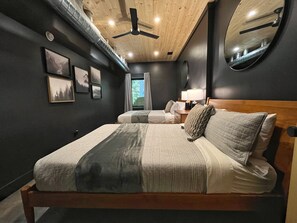 A bedroom with a bed, bedside tables, a mirror, and a ceiling fan. - Two Pines Hollow | Private A-Frame | Hot Tub (Rogers)