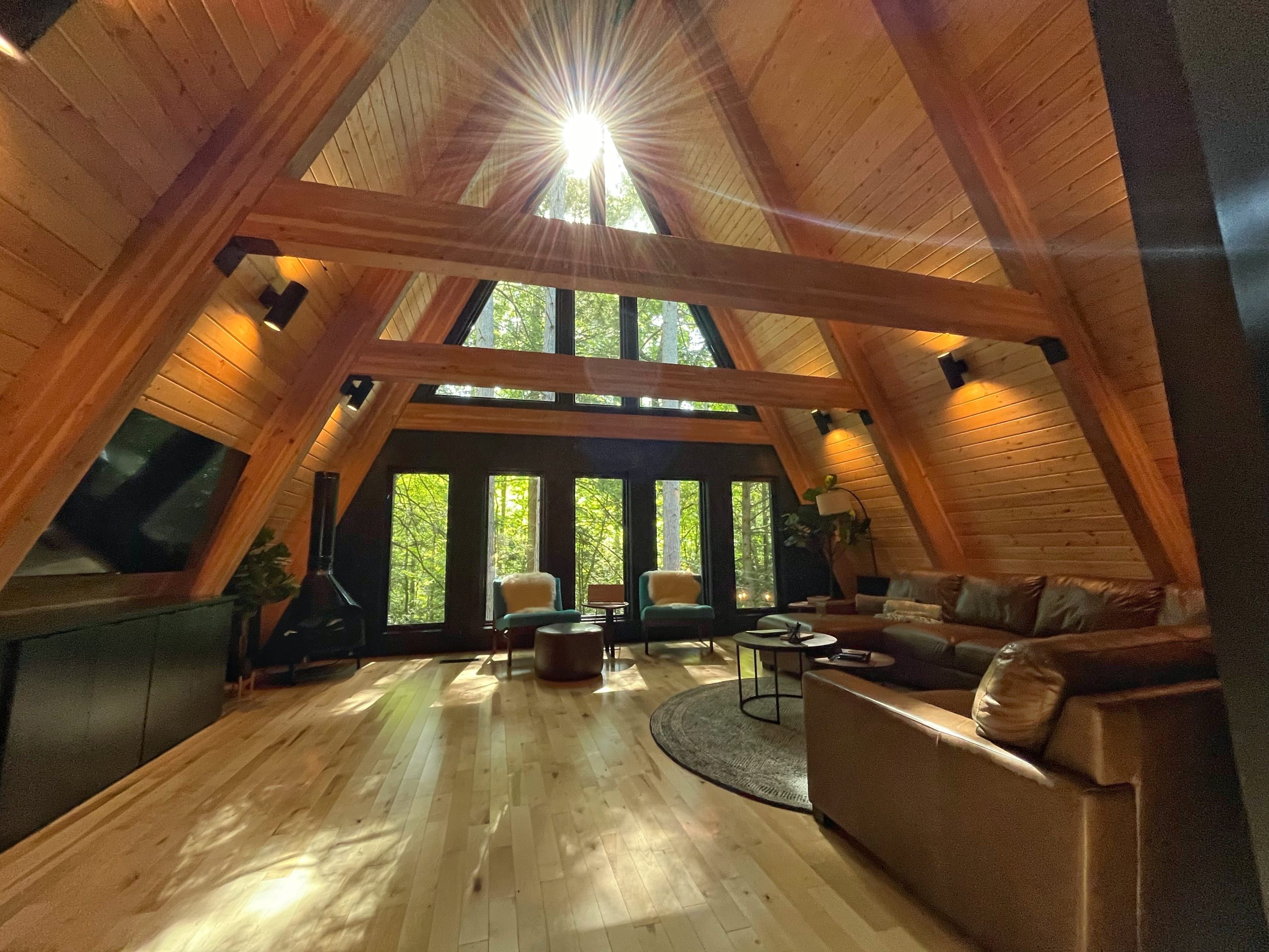 A high-ceilinged room with a wooden interior, a large window, and a sofa.
