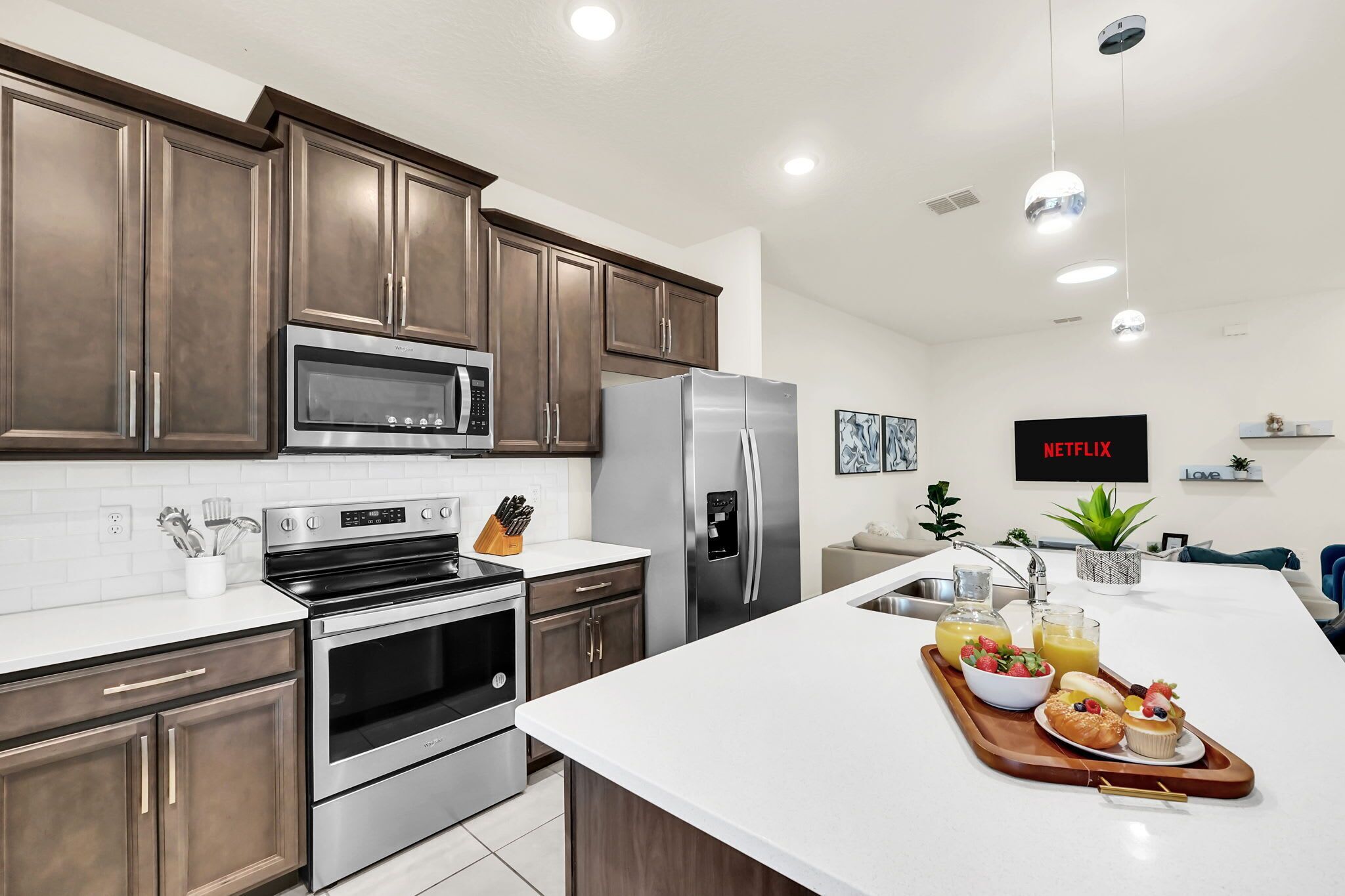 A modern kitchen with stainless steel appliances, a large island, and a breakfast tray.