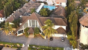 Ein Resort mit mehreren bungalowsähnlichen Gebäuden, einem Schwimmbad und Palmen.