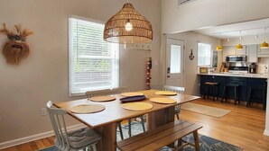 A modern kitchen with white cabinets, a central island, and yellow pendant lights.