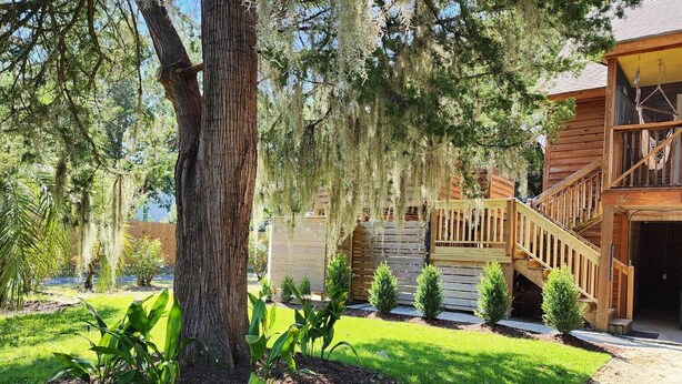 A wooden cabin with a porch and a staircase leading to a deck.